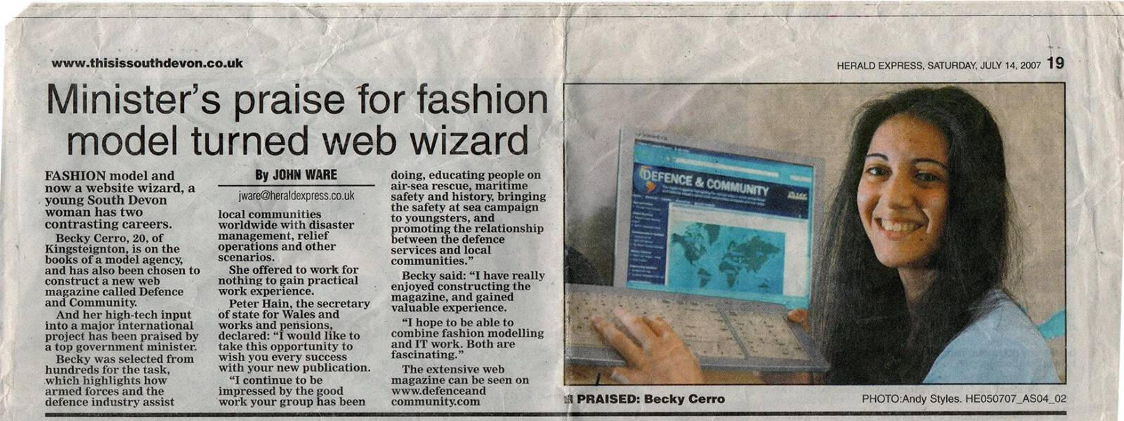 A scan of a newspaper article with the headline "Minister's praise for fashion model turned web wizard". There is a photo on the article of a woman holding a keyboard and a computer monitor in the background showing Defence & Community online magazine.